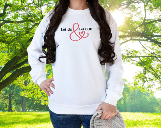White crewneck sweatshirt with the phrase ‘Let Go & Let God’ in bold black text and a red ampersand forming a heart. Cozy, inspirational faith-based apparel for everyday wear.